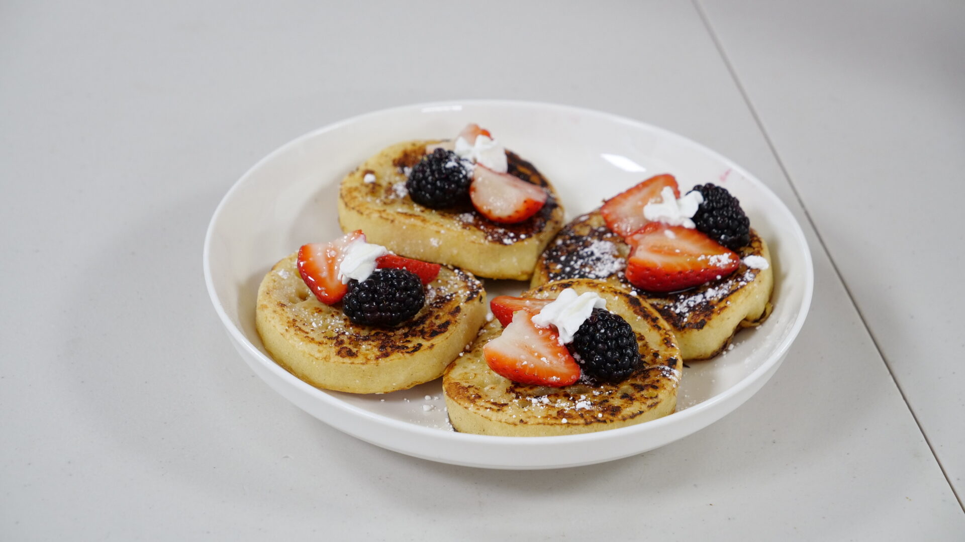 A plate of pancakes with strawberries and blueberries.