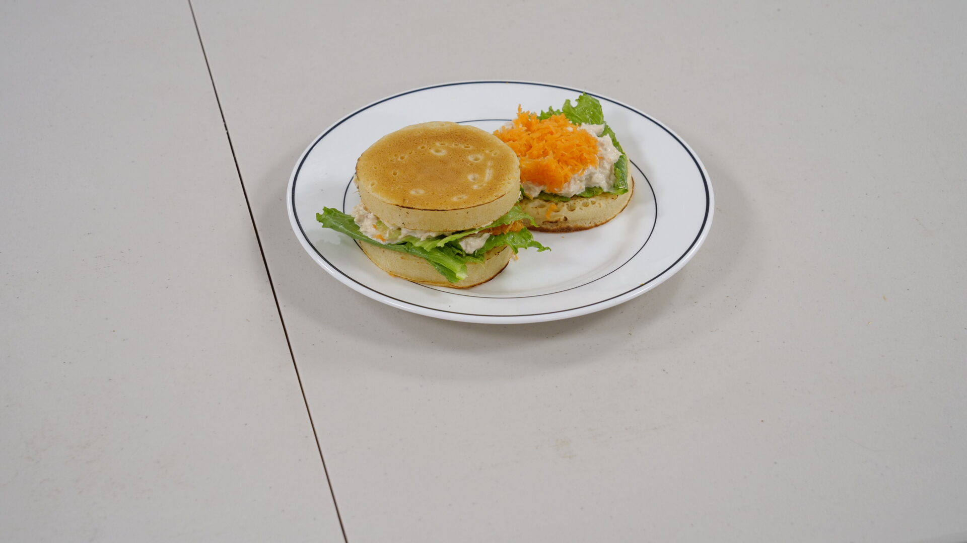 A sandwich on a plate with lettuce and carrot.