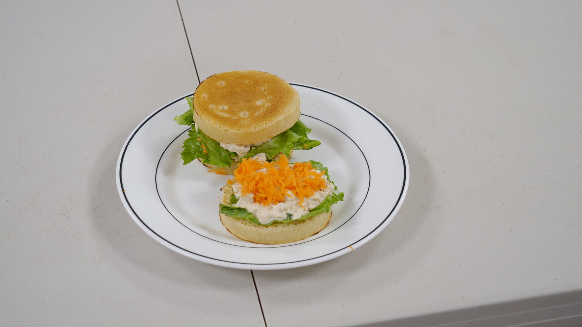 A sandwich on a plate with lettuce and orange.